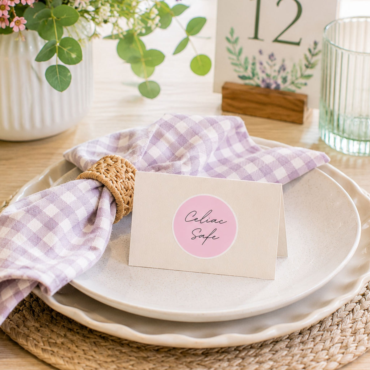 Pink celiac safe label shown on an elegant event place card with pastel table decor, florals, glassware, and a lavender gingham napkin.