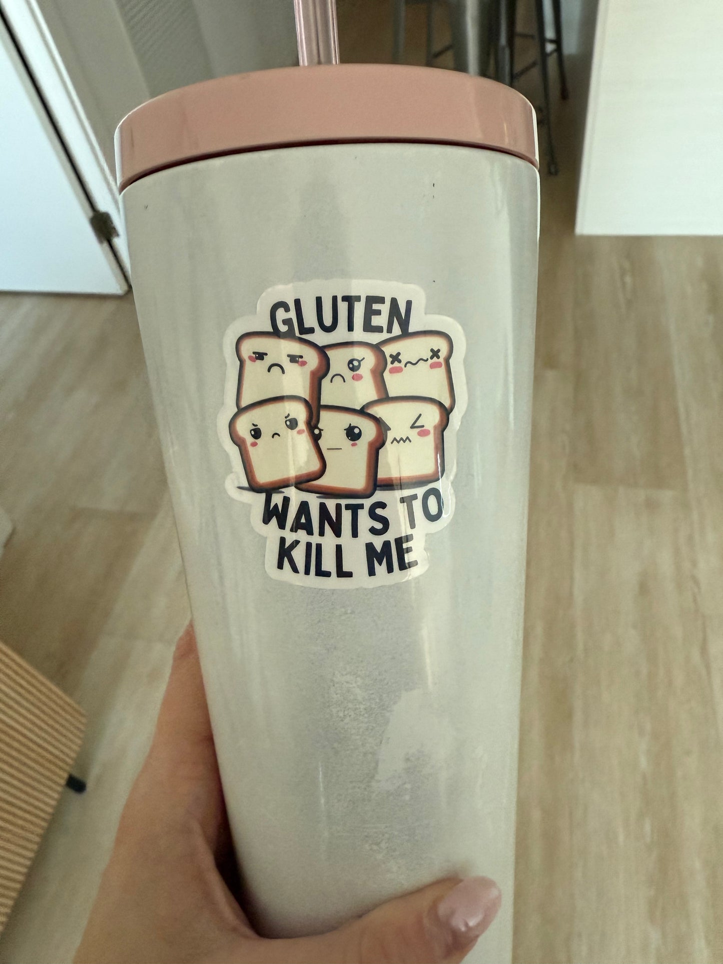 White water bottle with a pink lid featuring a “Gluten Wants to Kill Me” sticker with cute angry toast characters.